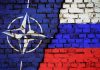 NATO logo and Russian flag painted on brick wall.