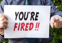 Person holding YOU'RE FIRED sign.